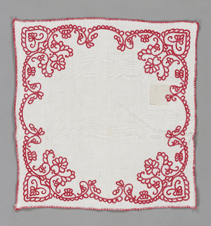 Cette serviette à pain densément texturée a été filée à la main et brodée avec des motifs floraux en coton rouge., © MCC/CMC, 76-358