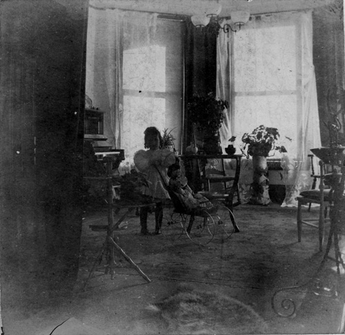 Portrait en pied de Marjorie Edith Holcroft, fille de Charles et Edith Holcroft, photographiée avec sa poupée dans le salon de sa maison, à Toronto, Ontarioo