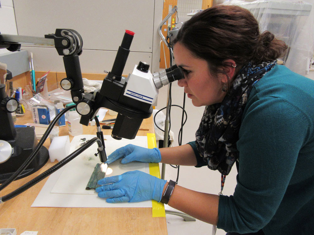 Une stagiaire examine un morceau de cuivre à l’aide d’un microscope