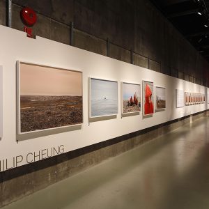 Un long espace d’exposition aux murs couverts d’images et de tableaux encadrés