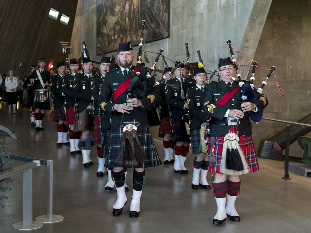 Un corps de cornemuses en tenue écossaise, marchant en deux rangées
