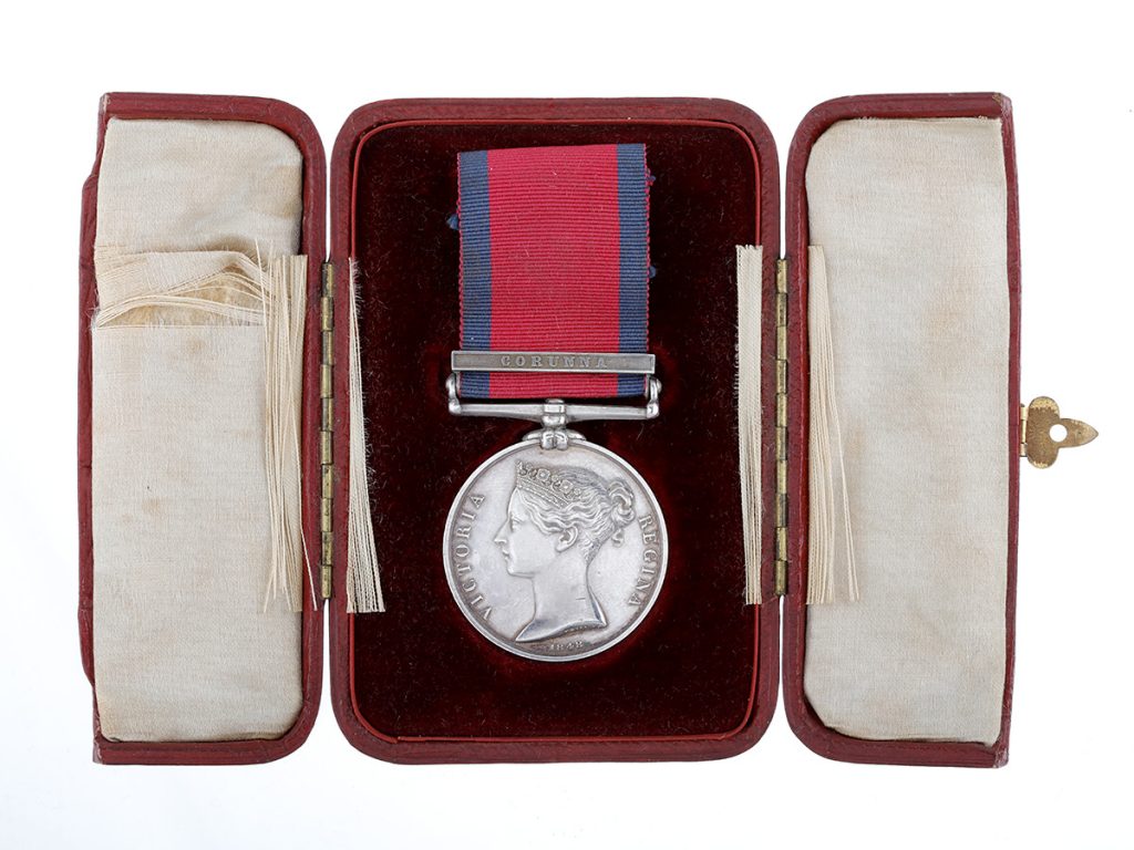 Un médaille militaire argent avec un ruban bleu et rouge, disposée dans un boitier brun doublé de noir et de blanc