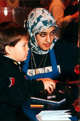 Une jeune femme voilée aidant un enfant. 