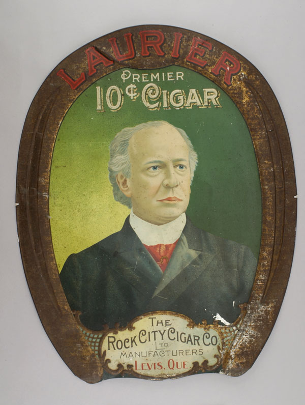 Enseigne publicitaire en étain de la Rock City Cigar Co. montrant une image de Laurier sur fond vert. Musée canadien de l’histoire, 1999.124.16
