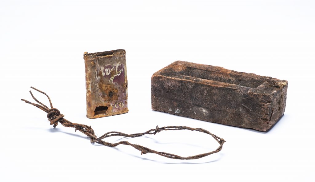 Tobacco tin, brick and barbed wire