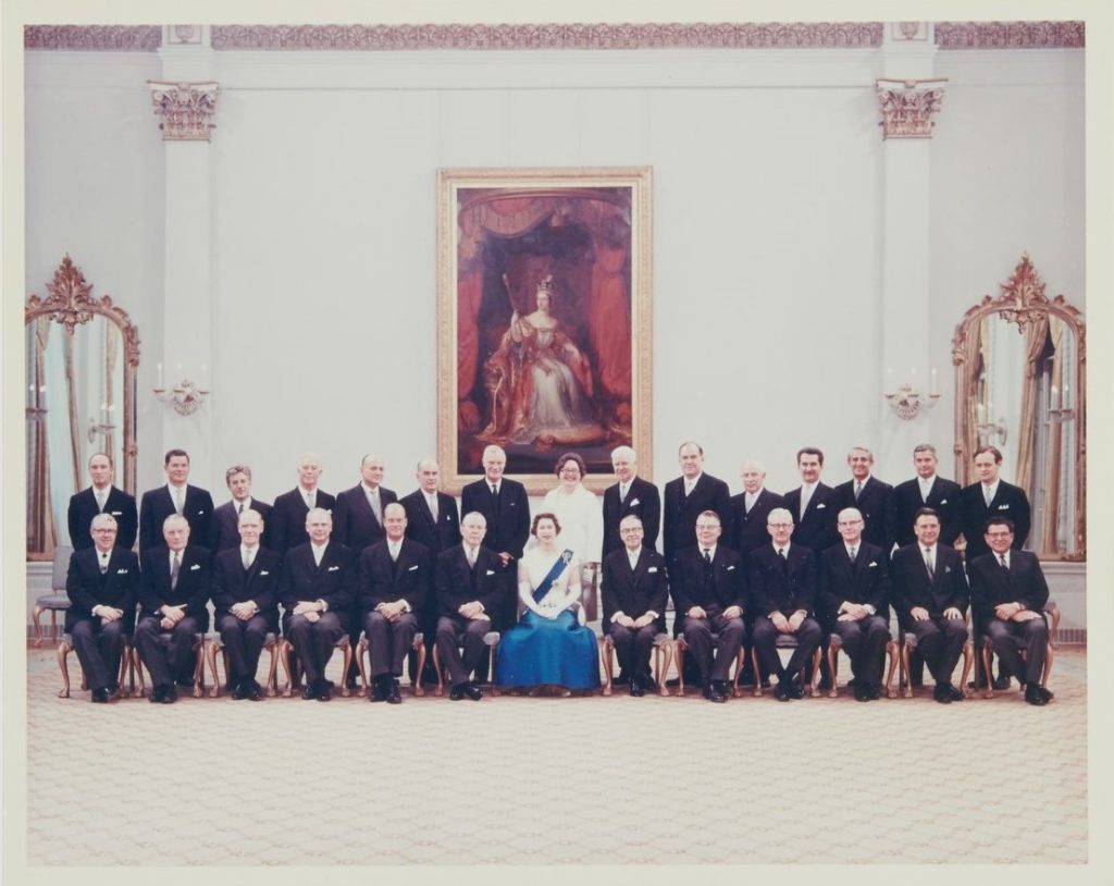 Conseil des ministres du Canada, 1er juillet 1967. La reine Élisabeth II et le premier ministre Lester B. Pearson sont au centre et 25 autres ministres en veston et cravate les entourent.