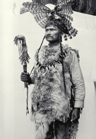 Homme nlaka'pamux (thompson) en costume traditionnel et tenant une massue de guerre, Spences Bridge, Colombie-Britannique, © MCC/CMC, J.A. Teit, 30986
