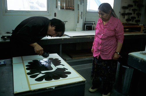 Kenojuak Ashevak et Qiatsuq Niviaqsi dans le processus de créer l'estampe Audacious Owl, créée par la technique de la gravure sur pierre et le pochoir Kenojuak Ashevak et Qiatsuq Niviaqsi dans le processus de créer l'estampe Audacious Owl, créée par la technique de la gravure sur pierre et le pochoir