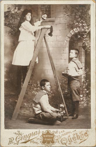 Photographie de trois enfants dans un jardin - deux garçons et une fille sur une échelle