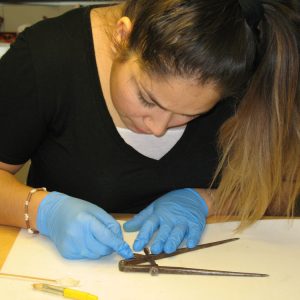 Une femme examine un outil métallique.