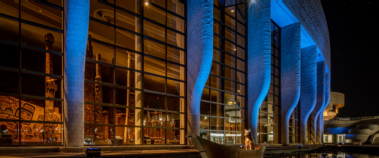 Le Musée canadien de l'histoire, situé à Ottawa, est un grand bâtiment sur lequel brille une lumière bleue.