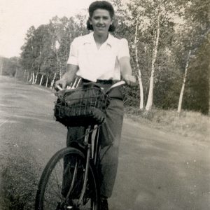 Une femme à bicyclette portant une chemise à col blanche et un pantalon