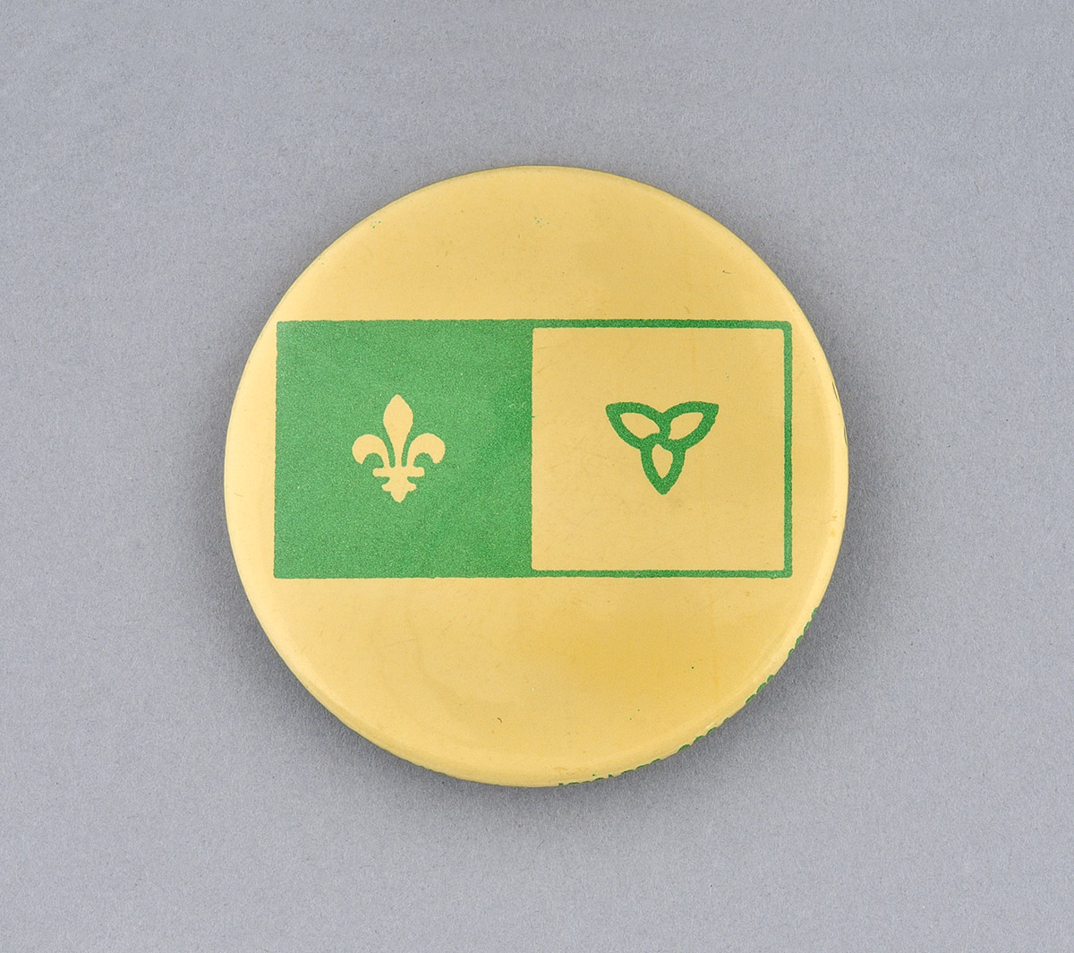 Un bouton vert et jaune avec une fleur de lys dessus, maintenant disponible au Musée canadien de l'histoire à Ottawa.