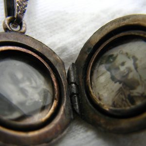 Un médaillon terni avec une photo de femme à droite