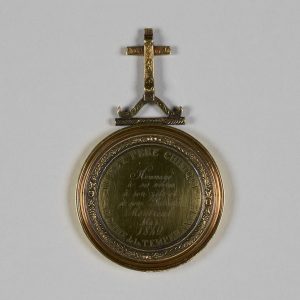 Médaillon circulaire avec une inscription et une croix sur le dessus