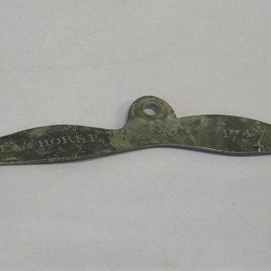 Plaque en métal corrodée présentant trois trous et l’inscription Sea Horse 1747