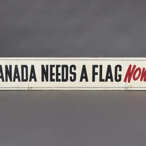 Panneau blanc avec lettrage noir et rouge indiquant « Canada needs a flag now! » (Un drapeau pour le Canada, ça presse!)