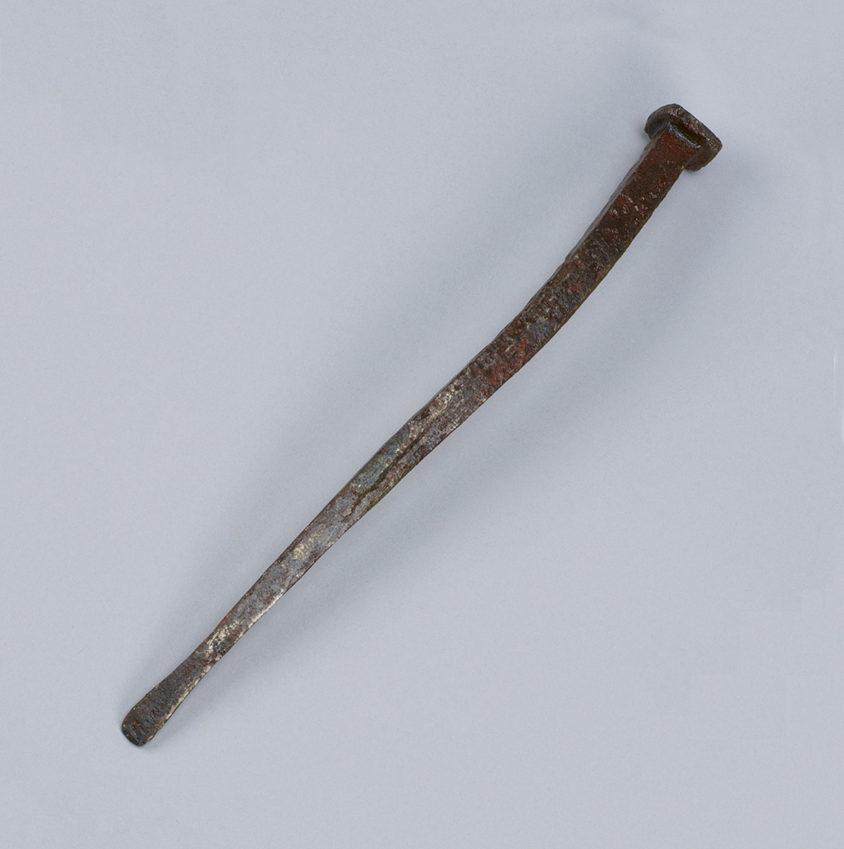 Un outil en métal rouillé sur une surface blanche exposé au Musée canadien de l'histoire à Ottawa.