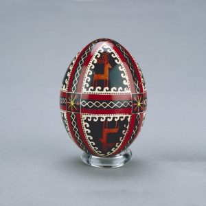 Un œuf de Pâques ukrainien décoré d’images en miroir de chevreuils, divisées par des formes de spirales et de rubans entrecoupées de fleurs.
