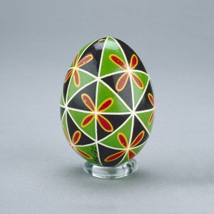 Un œuf de Pâques ukrainien décoré d’un motif de triangles noirs et verts entrecoupés de vives fleurs rouges et jaunes.