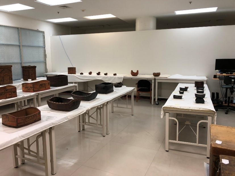 Une pièce blanche contenant plusieurs longues tables recouvertes de dizaines d’objets en bois de différentes tailles.