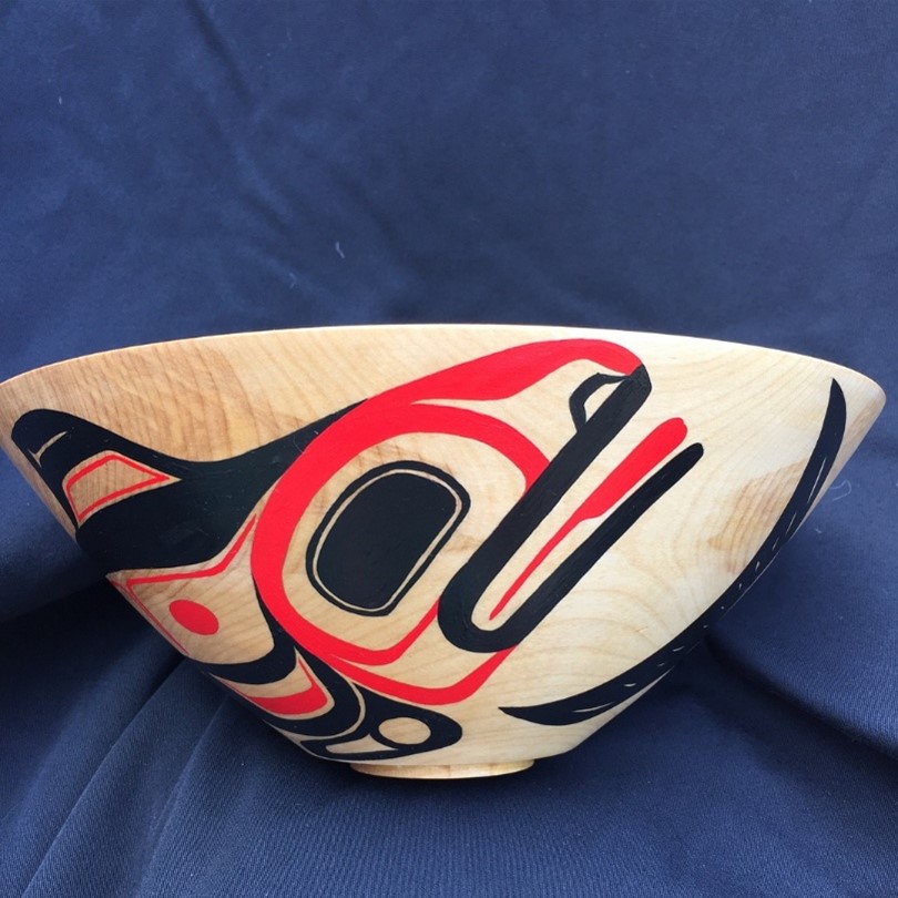 Un grand bol en bois sur lequel est peint une orque stylisée en noir et rouge.