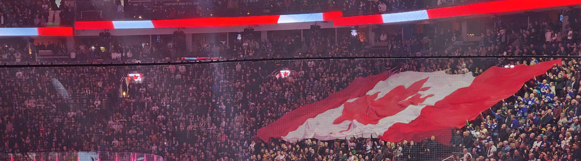 Dans un stade bondé, un énorme drapeau flotte au-dessus de la foule tandis que tous les yeux sont braqués sur les joueurs de hockey et les arbitres alignés sur la glace.