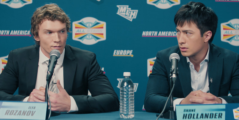 Deux joueurs de hockey portant des chemises et des vestes de sport sont assis devant des microphones.