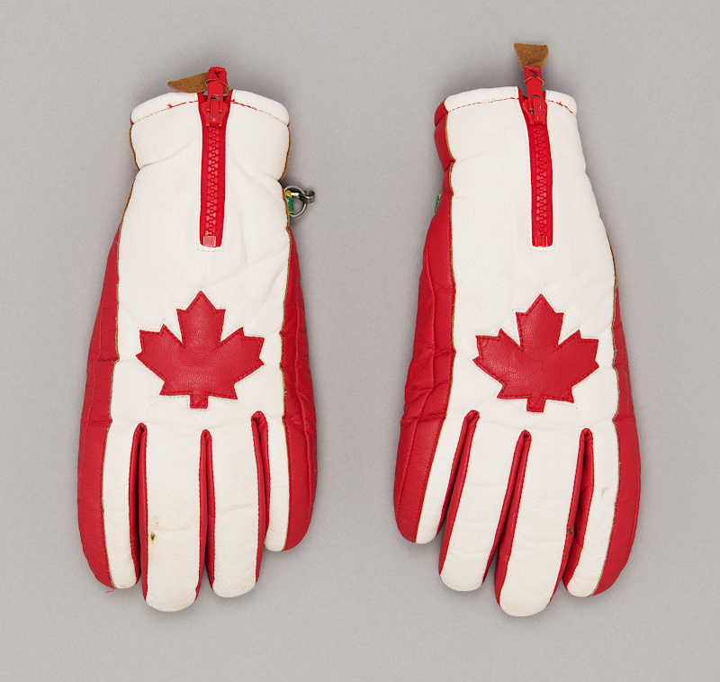 Gants de ski en cuir blanc avec des motifs rouges, dont une feuille d’érable sur le dos.