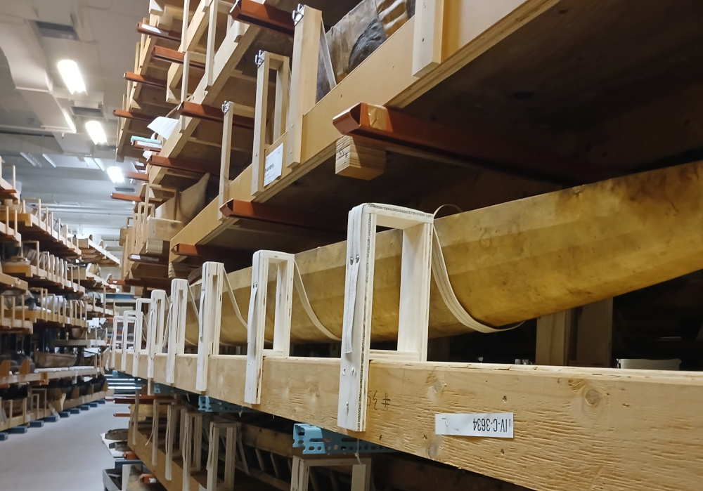 Une série de sangles en tissu attachées à des supports en contreplaqué permet de loger un kayak sur une étagère de rangement.