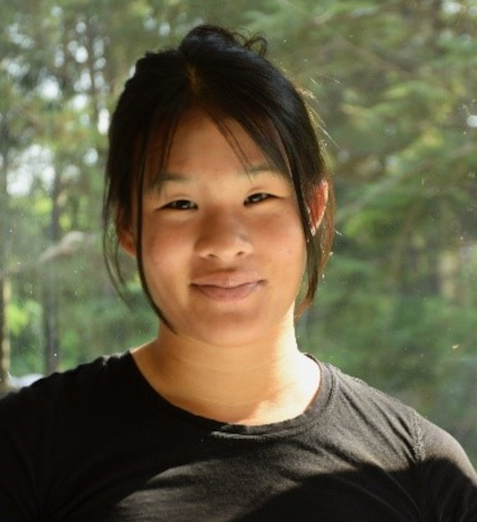 A medium-skinned person with long, straight dark hair wearing a t-shirt.